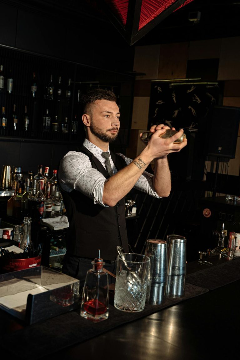 Bartender expertly shaking a cocktail in a dimly lit bar setting.