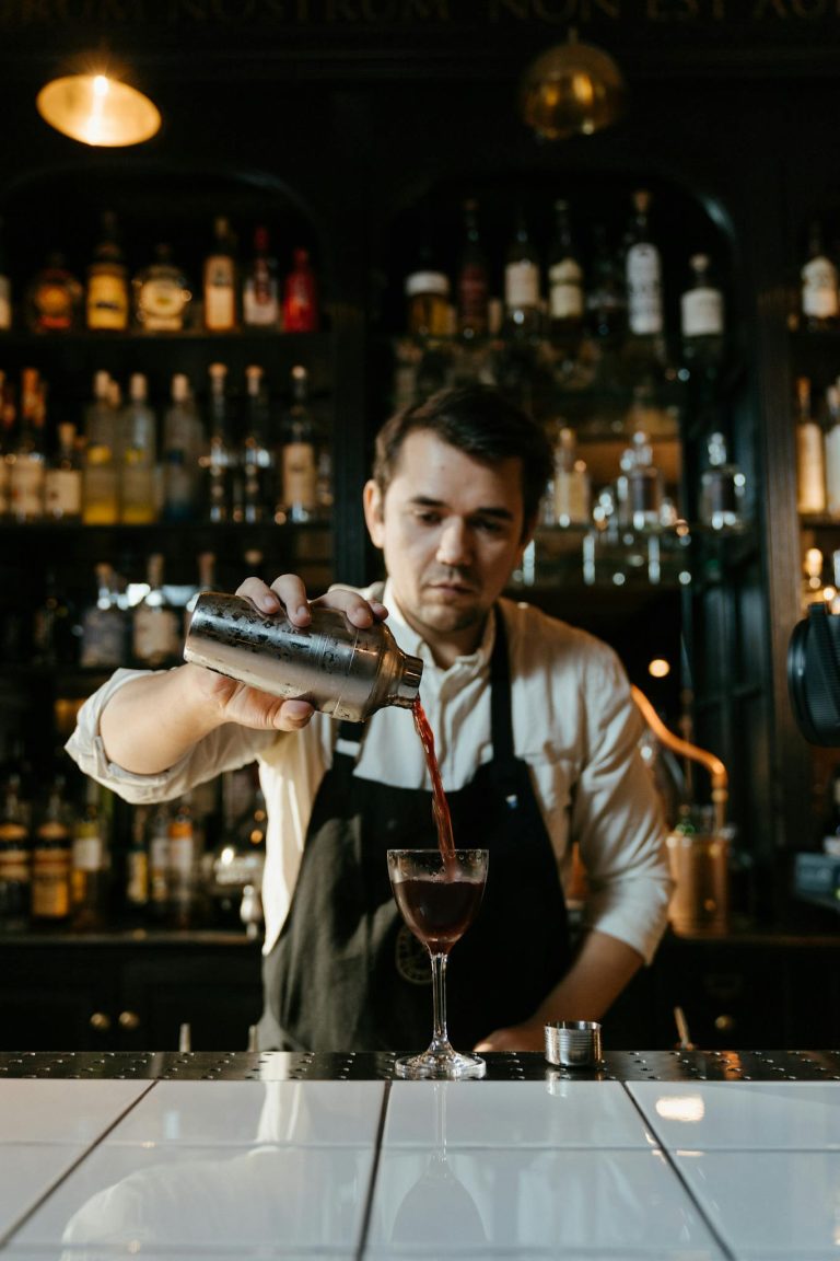 Bartender skillfully pours a cocktail at a stylish bar setting.